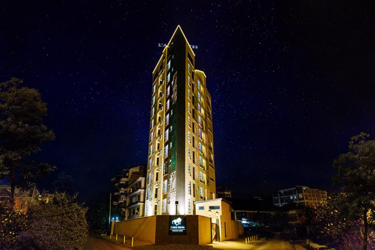 The exterior of L'Aziz Suites at night, lit for late arrivals.